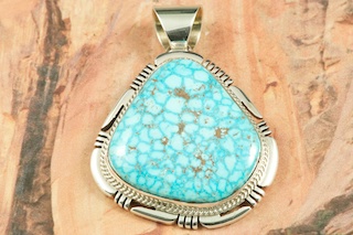 Genuine High Grade Kingman Web Turquoise set in Sterling Silver Pendant. Created by Navajo Artist Freddy Charley. Signed by the artist. The Mineral Park Mine, in the Cerbat Mountains 14 miles northwest of Kingman, was first mined by Indians centuries before white man came to the area. It is one of the three sites of prehistoric mining localities in the state of Arizona. Mineral Park was the most extensively worked area by the Indians of the three. S.A. �Chuck� Colbaugh found a cache of stone hammers uncovered in ancient trenches and tunnels, when he had the turquoise mining concession in May of 1962. Ithaca Peak and Turquoise Mine (formally called Aztec Mountain or Aztec Peak) are the most famous of the peaks in the area containing turquoise. Free 18